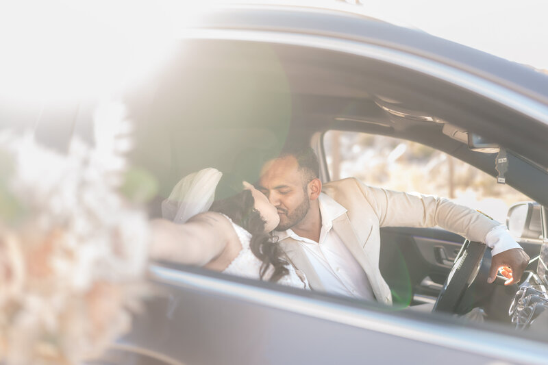 Joshua Tree Elopement Bride and Groom at Hidden Valley elopement kissing and driving away in car celebrating.