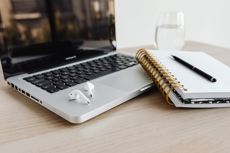 kaboompics_laptop-compter-desk-glass-of-water-macbook-airpods-earphones-notebook-pen-25490