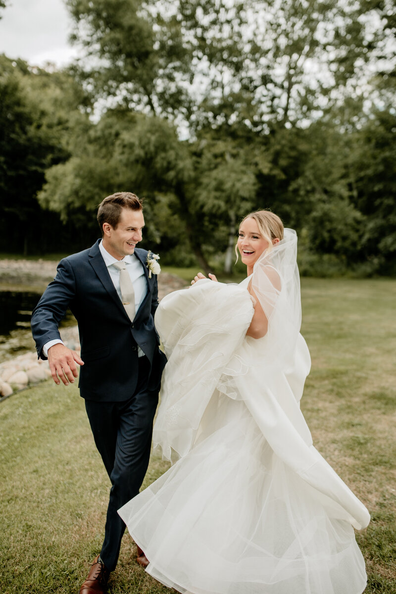 Bride and groom frolic on the lawn following their emotional first look during their Wisconsin wedding.