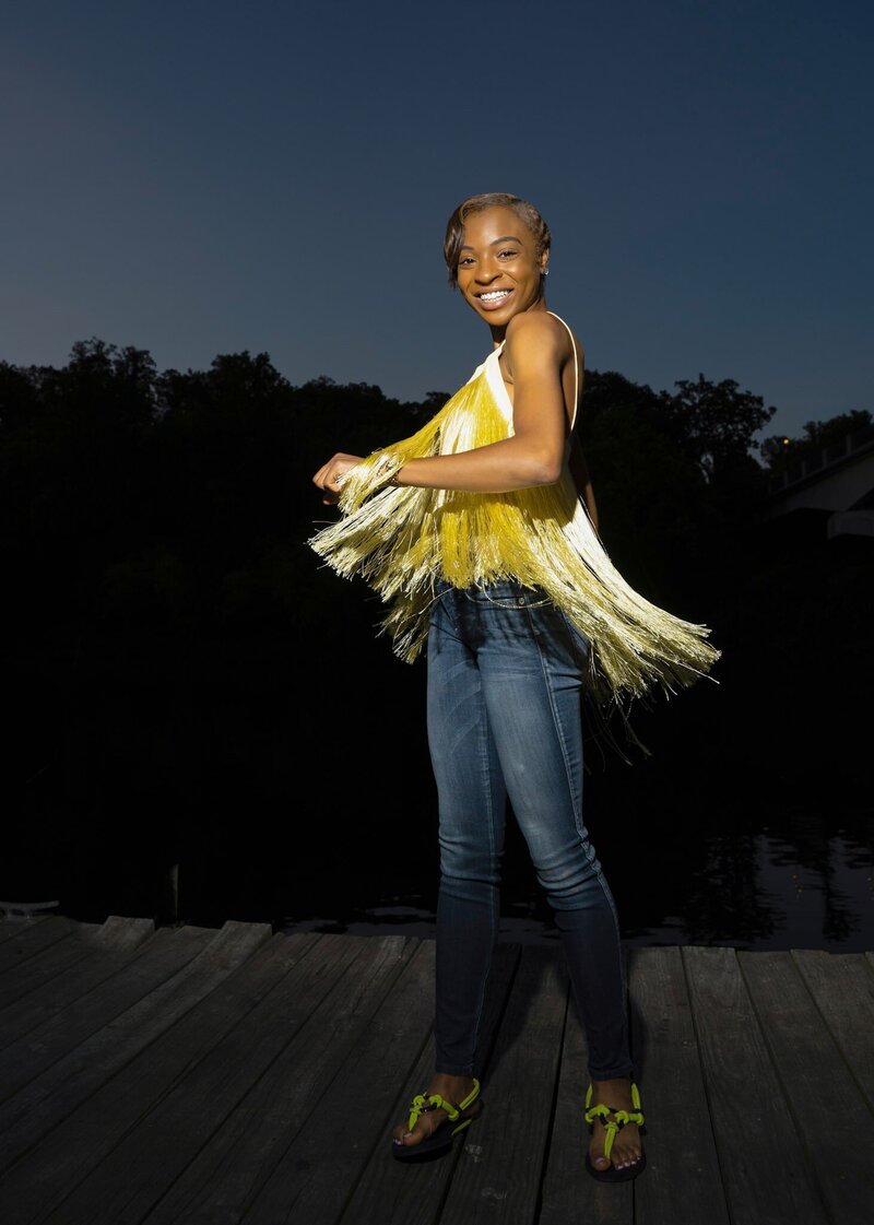 An African American woman in a yellow blouse dances on the dock in Occoquan, Virginia.