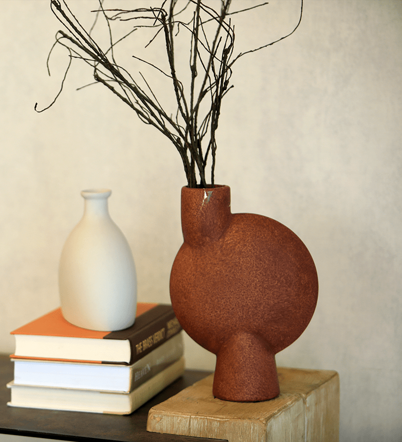 Rustic vase with twigs and books on wooden block