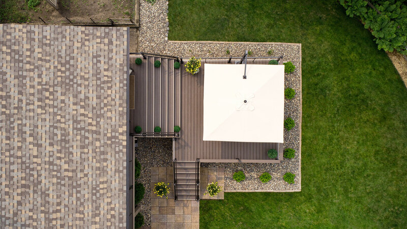 Aerial view of a low-maintenance deck with two staircases and a large white square umbrella. 