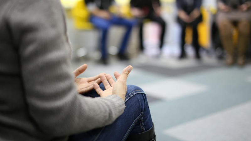 Therapy session with individuals engaged in open conversation, supporting ADHD-related emotional and relational growth