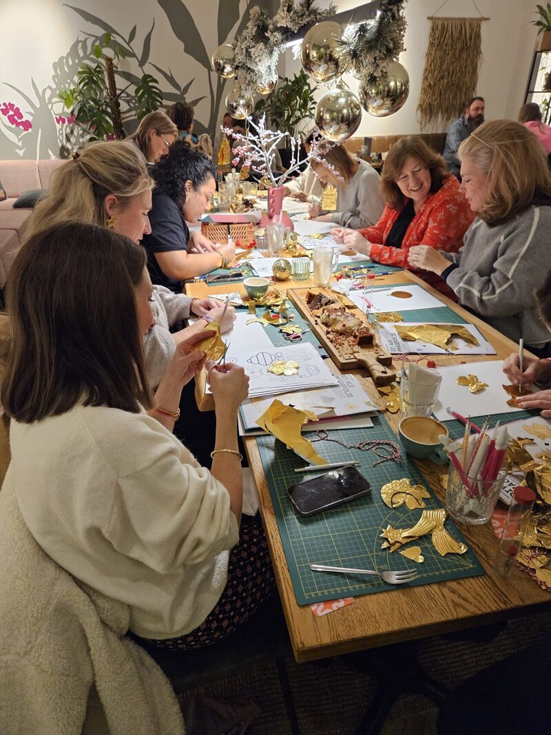 Goudfolie workshop groep deelnemer in actie tijdens workshop bij een lunchroom aan grote tafel.