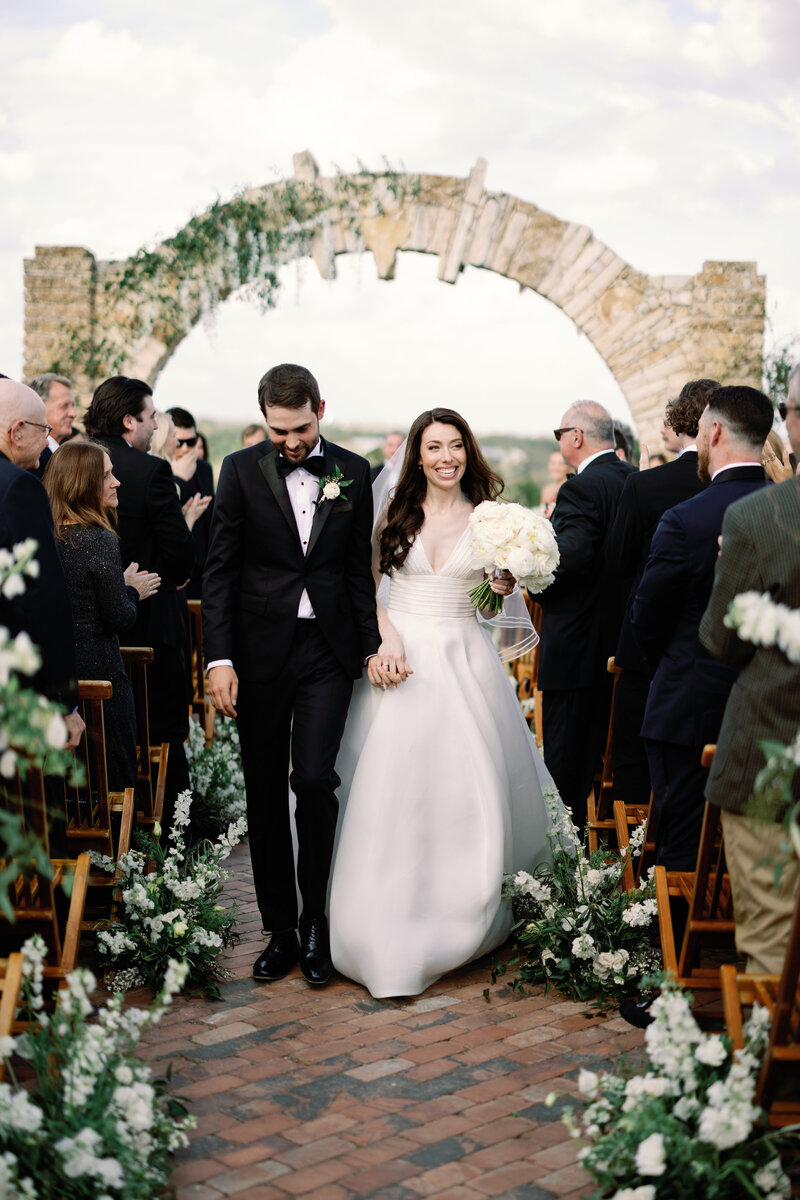 Bride and groom walking down the aisle after their ceremony at Camp Lucy in Austin, Texas. A joyful wedding moment.
