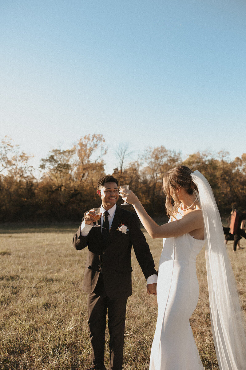 intimate elopement in park in kansas city mo. white dress from lulu weddings. black tux classic mens outfit for wedding. cathedral length veil on bride