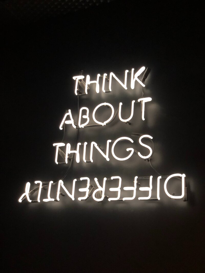White neon sign that says "Think About Things Differently"