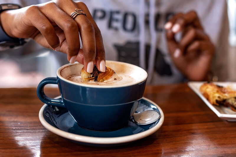 Black female dipping a pastry in her expresso
