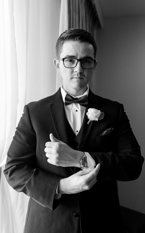 Classy black and white image of a groom adjusting handcuffs detail shot at a St Augustine wedding