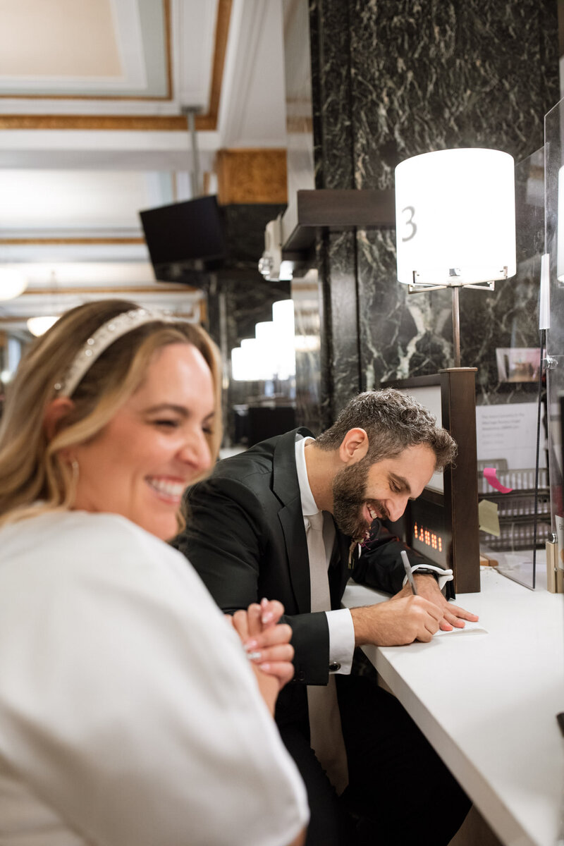 NYC city hall couple signing marriage license and laughing