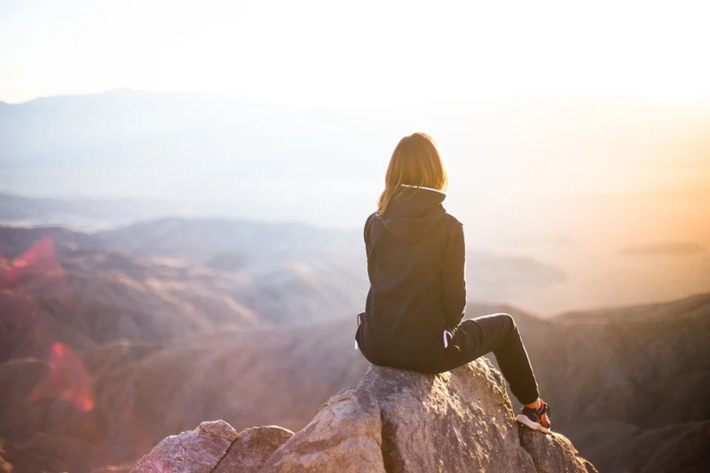 woman sitting on a high mountain top looking outward