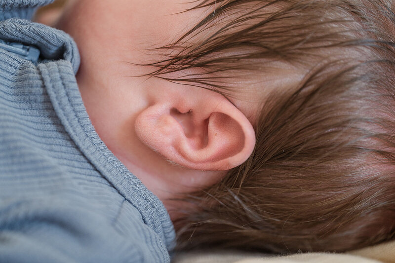 close up of newborn baby ear with a lot of hair and blue outfit by lancaster pa photographer