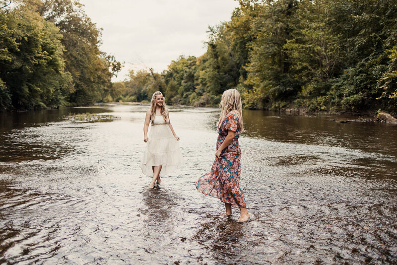 Senior sisters wearing beautiful dresses playing in the creek water. 