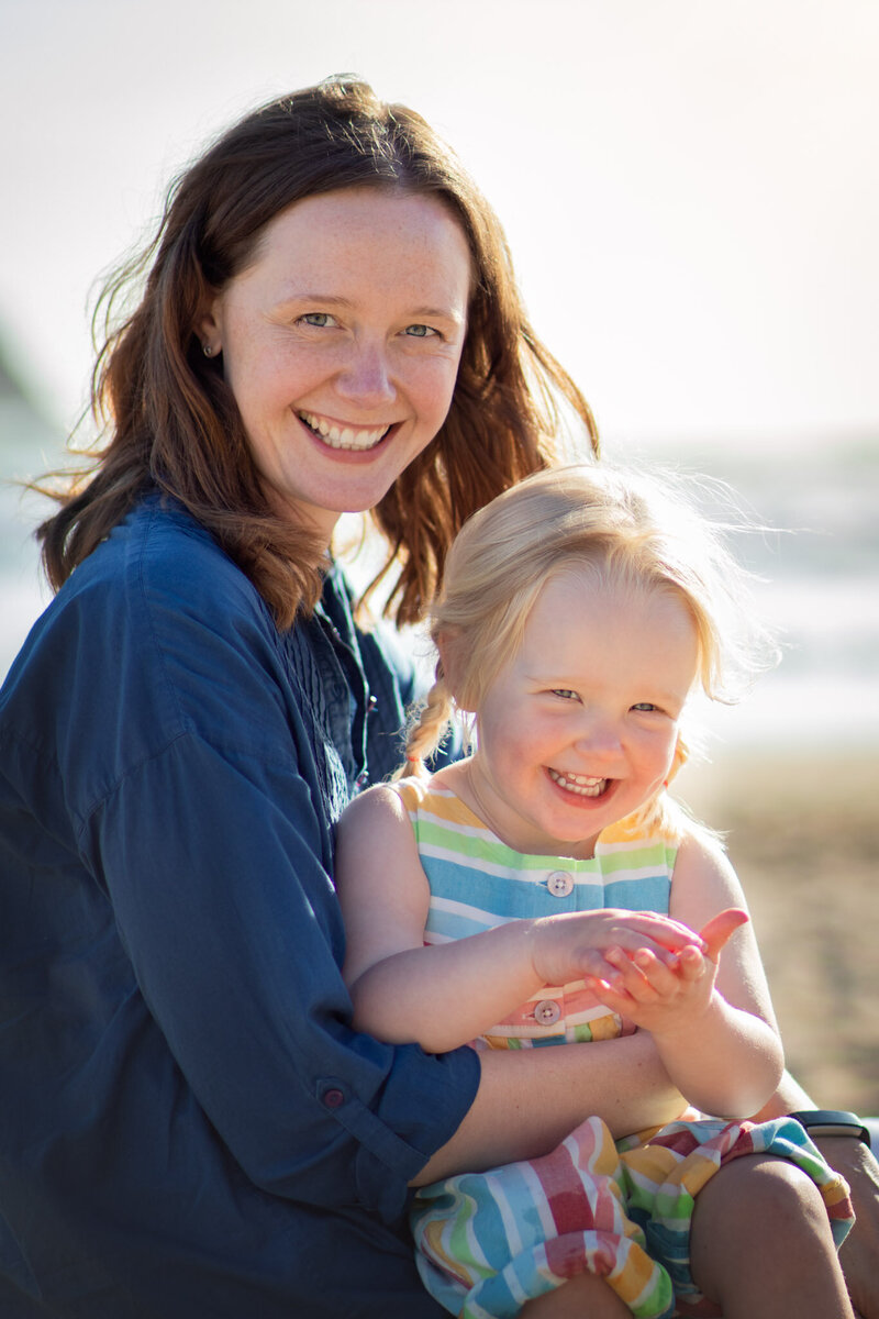 Mother sits with her daughter smiling on her lap