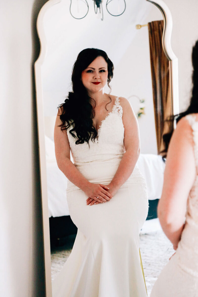 A bride sitting in front of a mirror in her gown, reflecting elegance