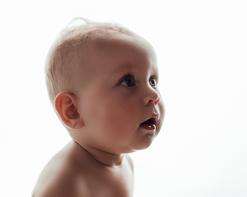 Laughing baby playing peekaboo during one-year milestone session