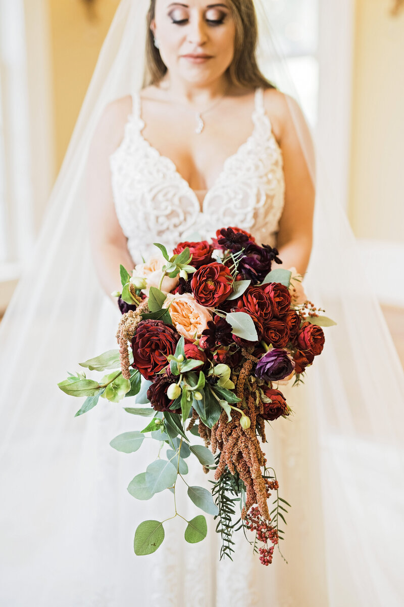 Closeup of a bridal bouquet with large red flowers and handing vines.