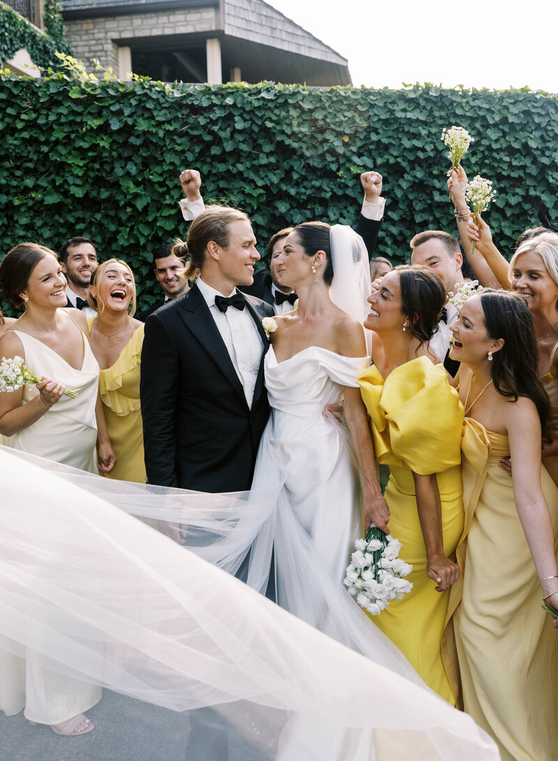 photo of bride and groom staring at each other while the wedding party cheers and the veil is swooped in front of them taken by Mansfield Wedding Photographer, Annie Trammel