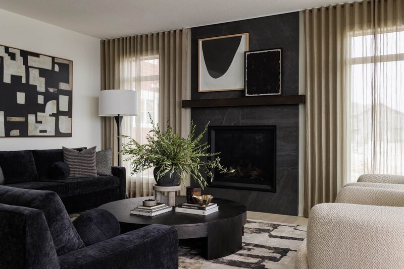 A cozy living room with charcoal upholstered sofas, gold accents and abstract black and white art. 