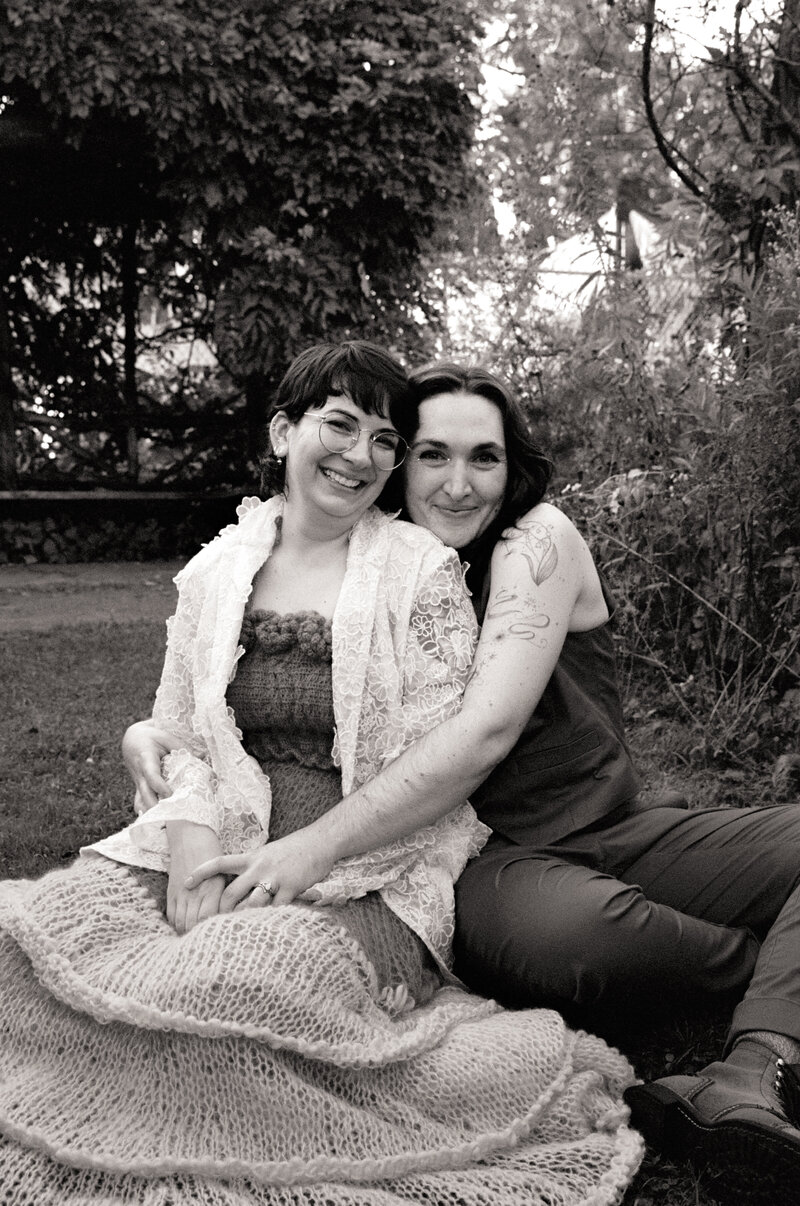 Queer couple photographed sitting in a garden together after they elope in western Massachusetts by a queer film wedding photographer at Castillo Holliday Photo + Film.