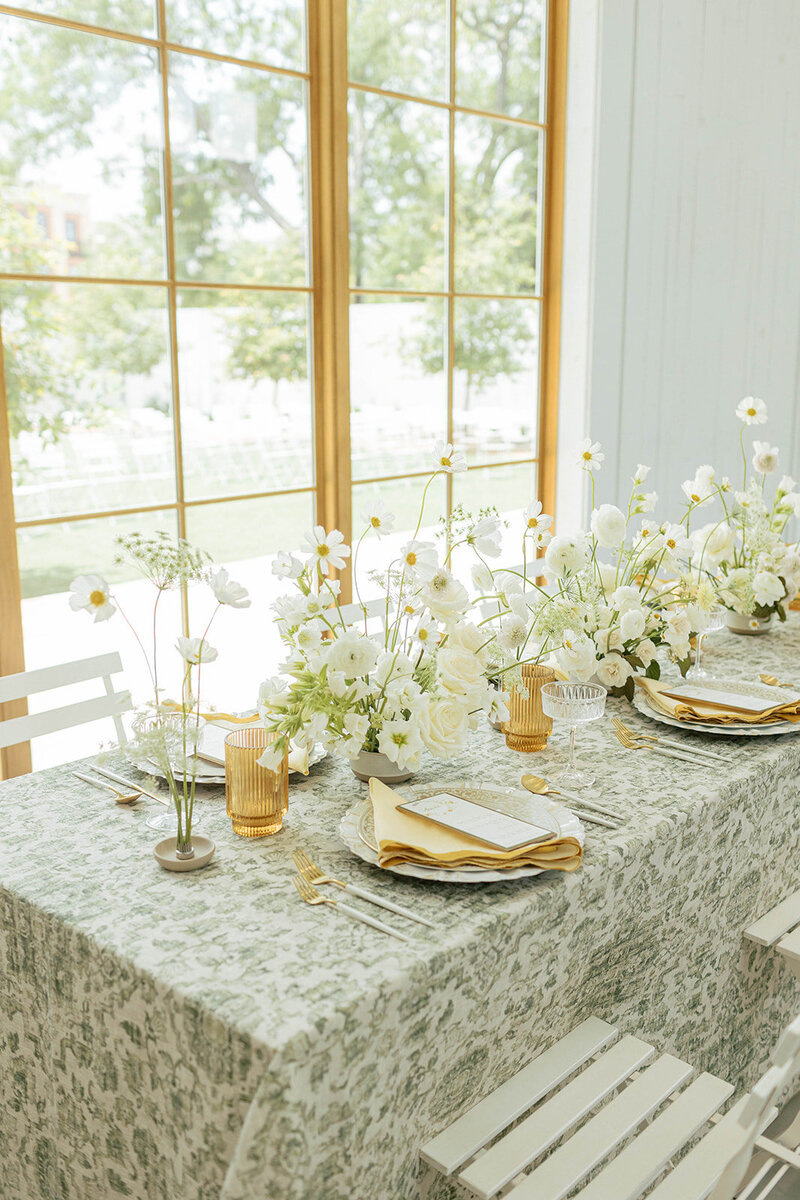 Chic wedding tablescape with white florals, patterned linens, amber glassware, and layered place settings, designed by Eventive Designs in Austin, Texas.