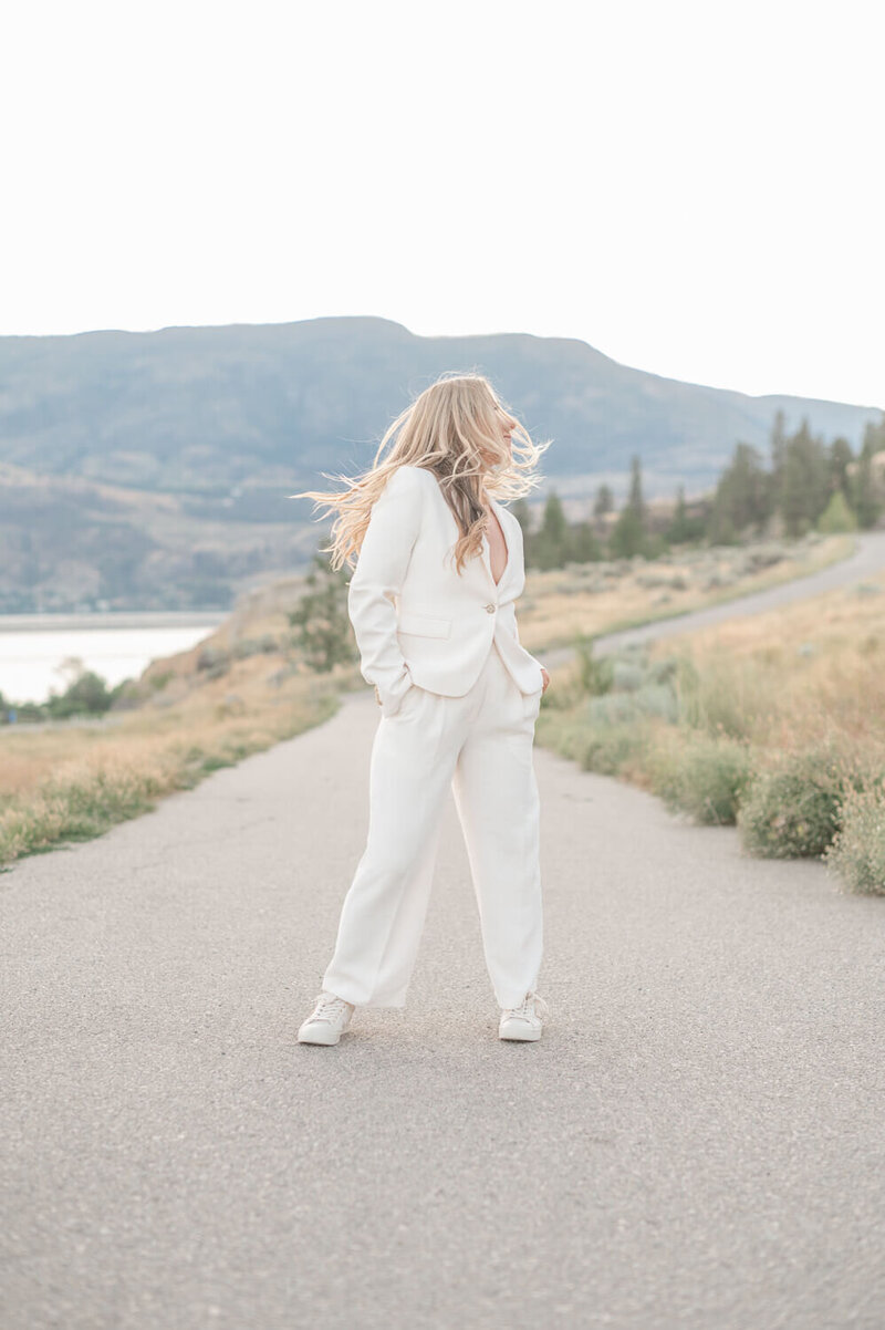 Storycatcher photographer, Kristen standing on outdoor path and swinging her hair