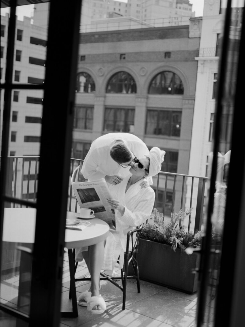 bride in bathrobe, head towel, sunglasses kissed by her fiancé, Shinola Hotel balcony brunch, wedding morning, engagement session
