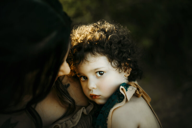 mom holds toddler s she looks into the camera