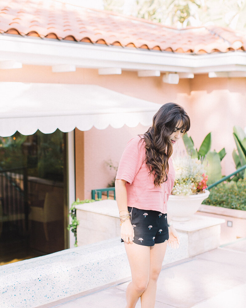 Candid photo of a girl outside wearing a pink shirt and black shorts
