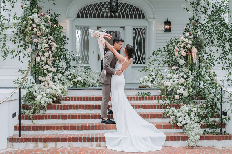 Bride throws arms around groom with ceremony flowers in the background