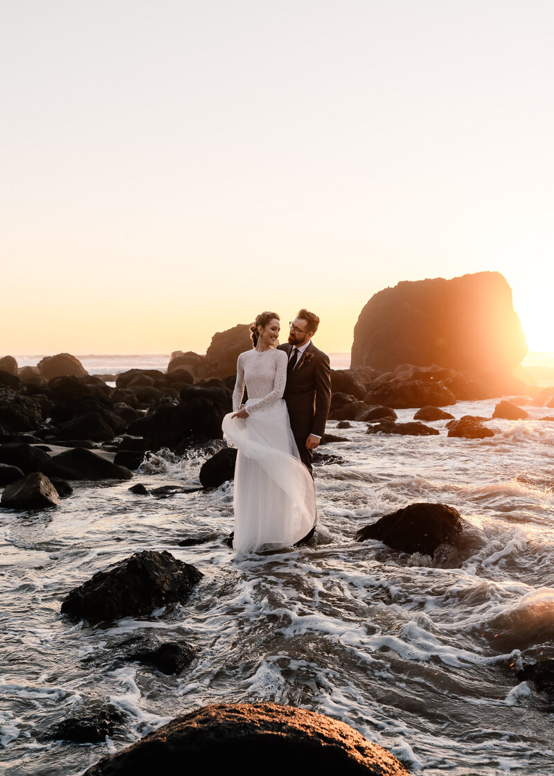 During their oregon coast elopement a bride and groom seemingly stand on top of the swirling waves  swell beneath them