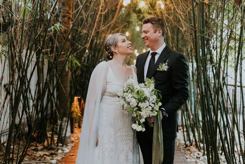 Jess and Branden surrounded by bamboo and staring at each other. I should mention she's holding her gorgeous white and green bouquet.