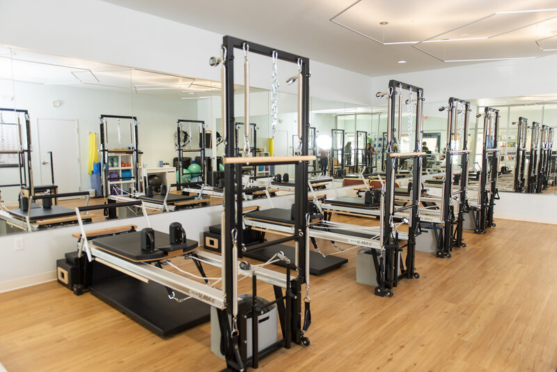 A wide shot of a Pilates studio shows customers the equipment