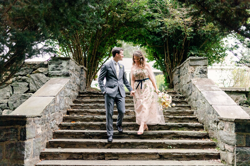 groom and bride hand in hand walking down cobblestone steps