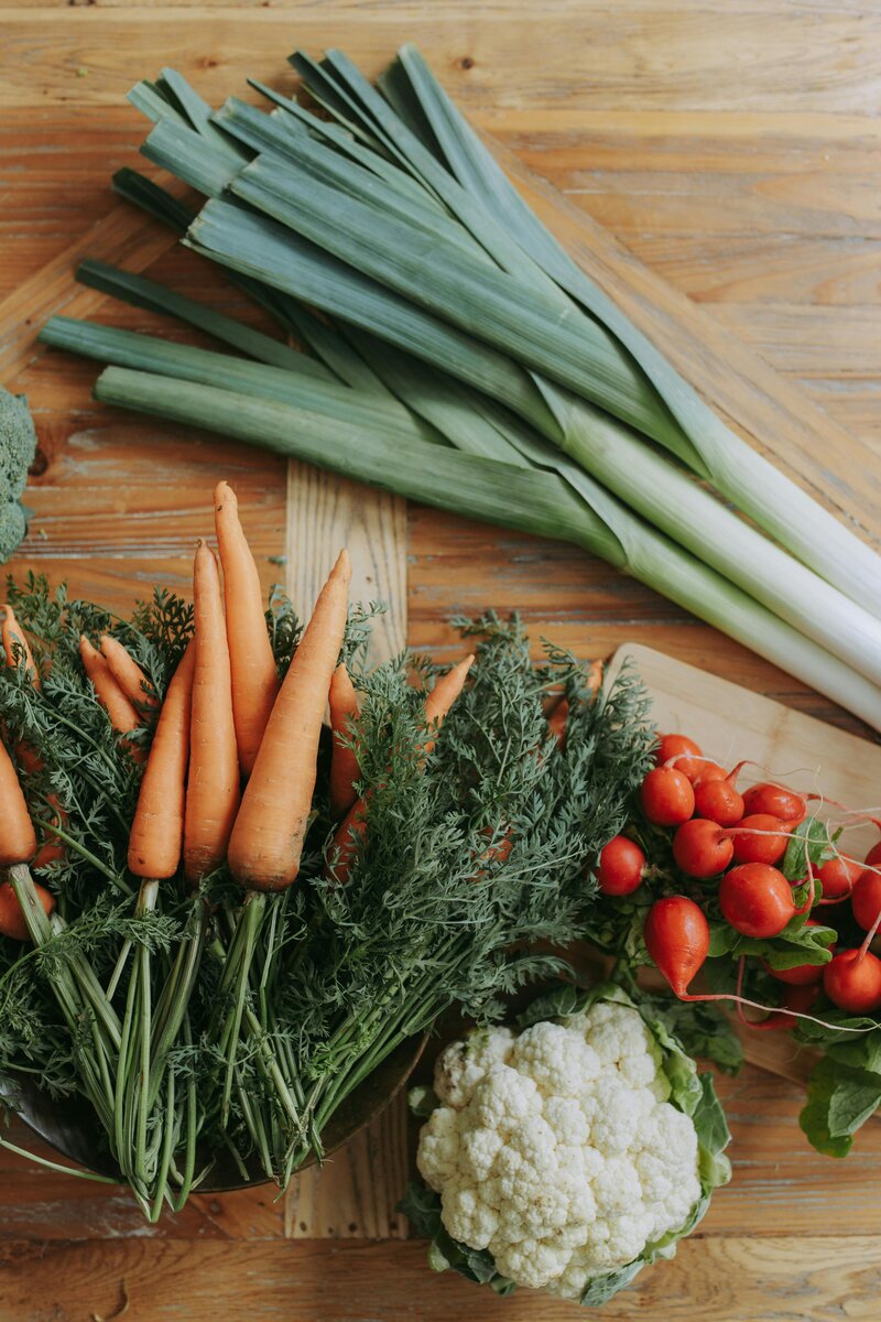 A table displaying various fresh vegetables alongside a wooden cutting board, emphasizing healthy eating for nutritional counseling.
