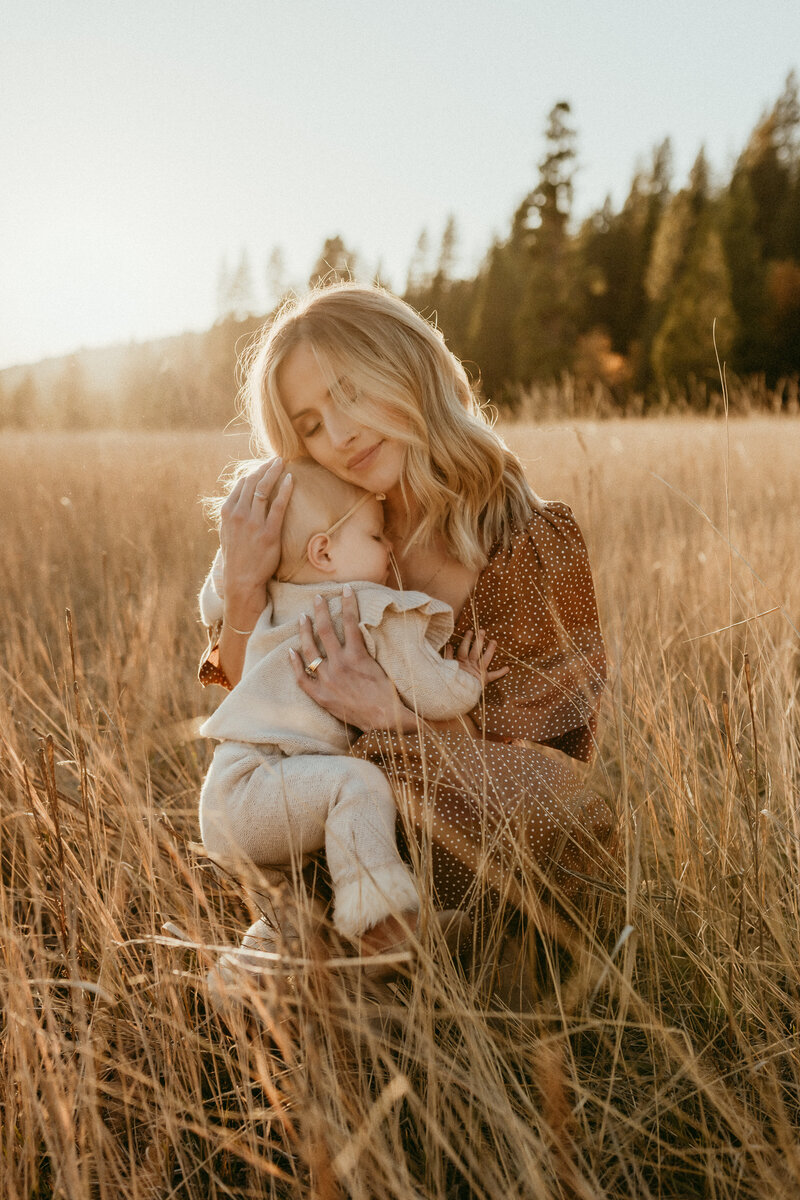 A woman holding a baby walking down a dirt road.