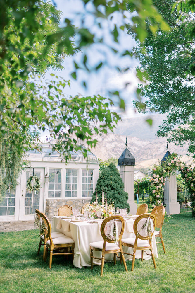 square tablescape next to greenhouse at wadley farms in lindon, utah with mountains and floral arch in background