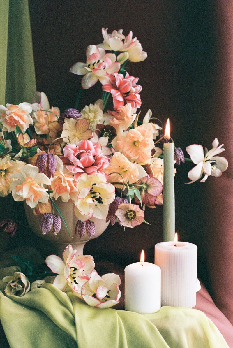 stylized shot of pink and peach floral bouquet next to lit candles on table taken by minnesota wedding photographer tom thornton