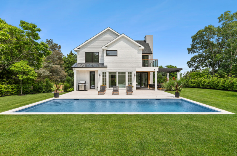 Black wood modern farmhouse venue rental featuring muskoka chairs and a pool
