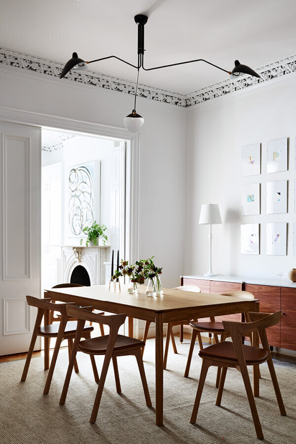 Interior decorators in Boston create a modern dining room in a historic brownstone, blending classic details with contemporary style by Sarah Scales Design.
