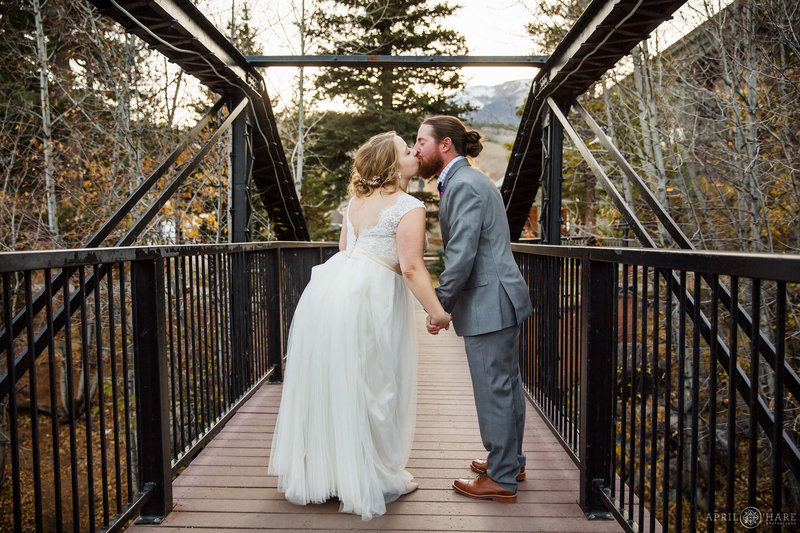 Wedding couple kiss on the historic metal bridge over the Blue River at Silverthorne Pavilion in Colorado