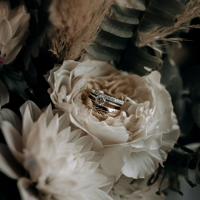wedding rings in wedding bouquet with white flowers, pampas, and eucalyptus