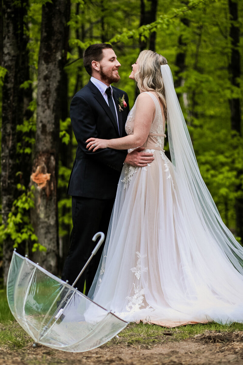 Bride and Groom standing together facing each other, umbrella on ground