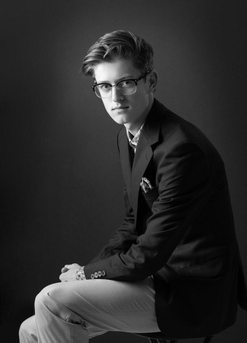 A black and white portrait of a senior boy in a suit coat