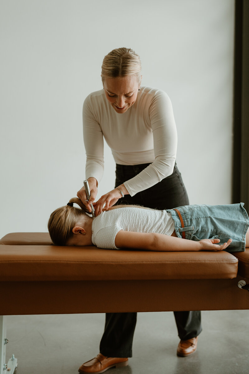 woman adjusting child on chiropractic table with TRT