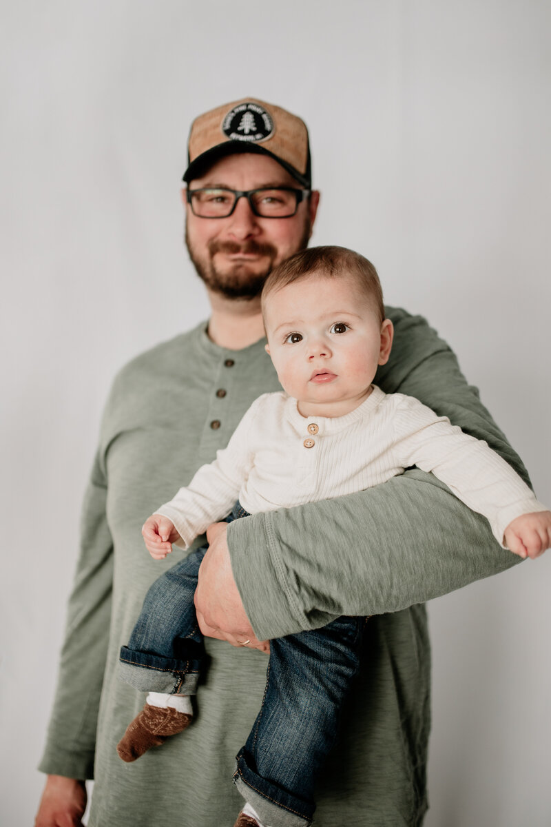 Dad proudly holds his six month old son during an in-home family session in Duluth, Minnesota.