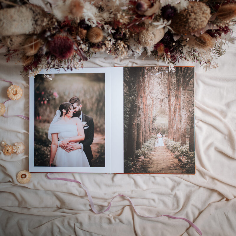 Wedding album open to spread of bride and groom in the forest