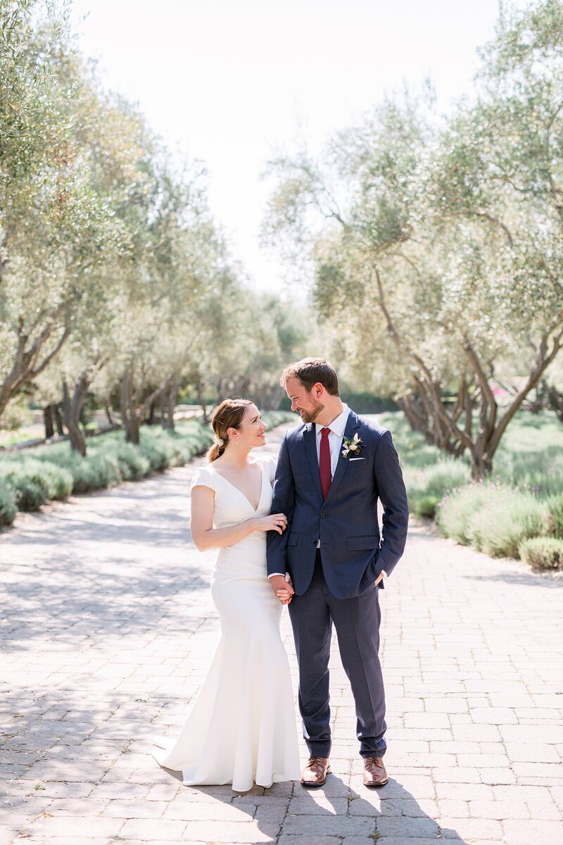 Bride and groom hold hands and smile in front of a blue door at their Santa Barbara wedding