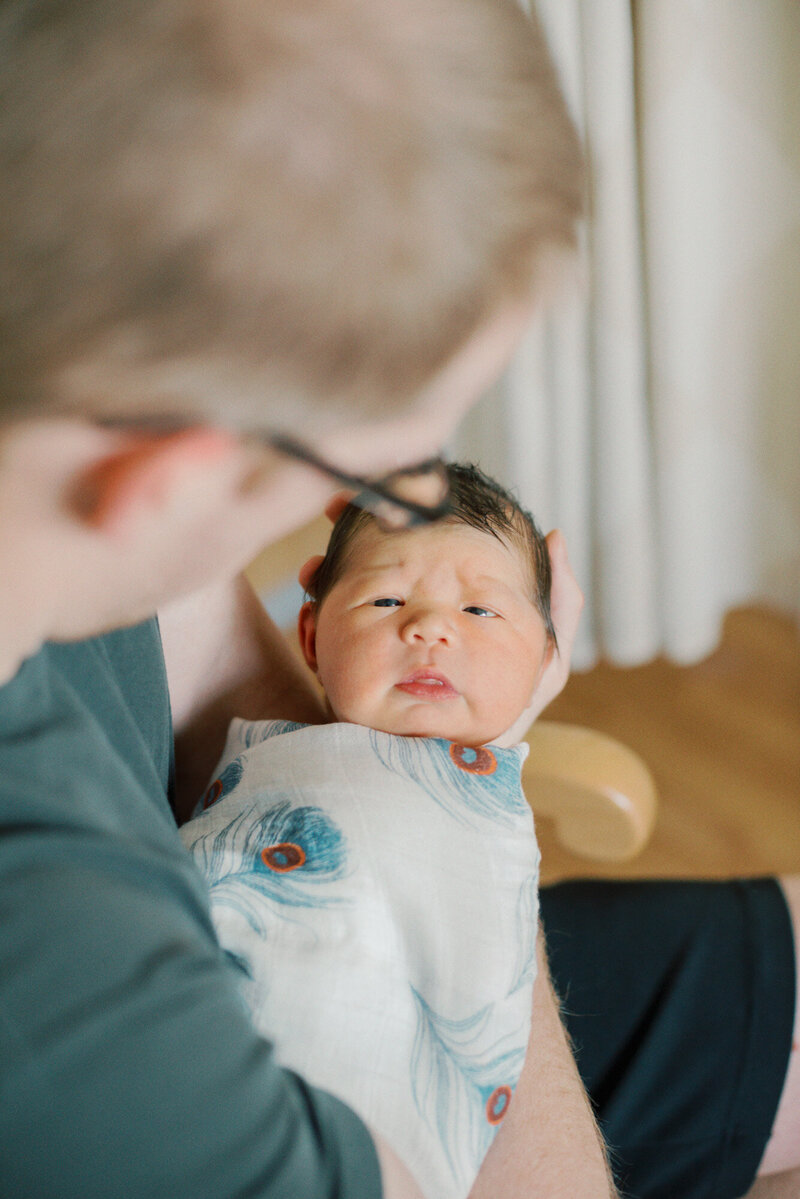 father holding newborn son in hospital for newborn photos