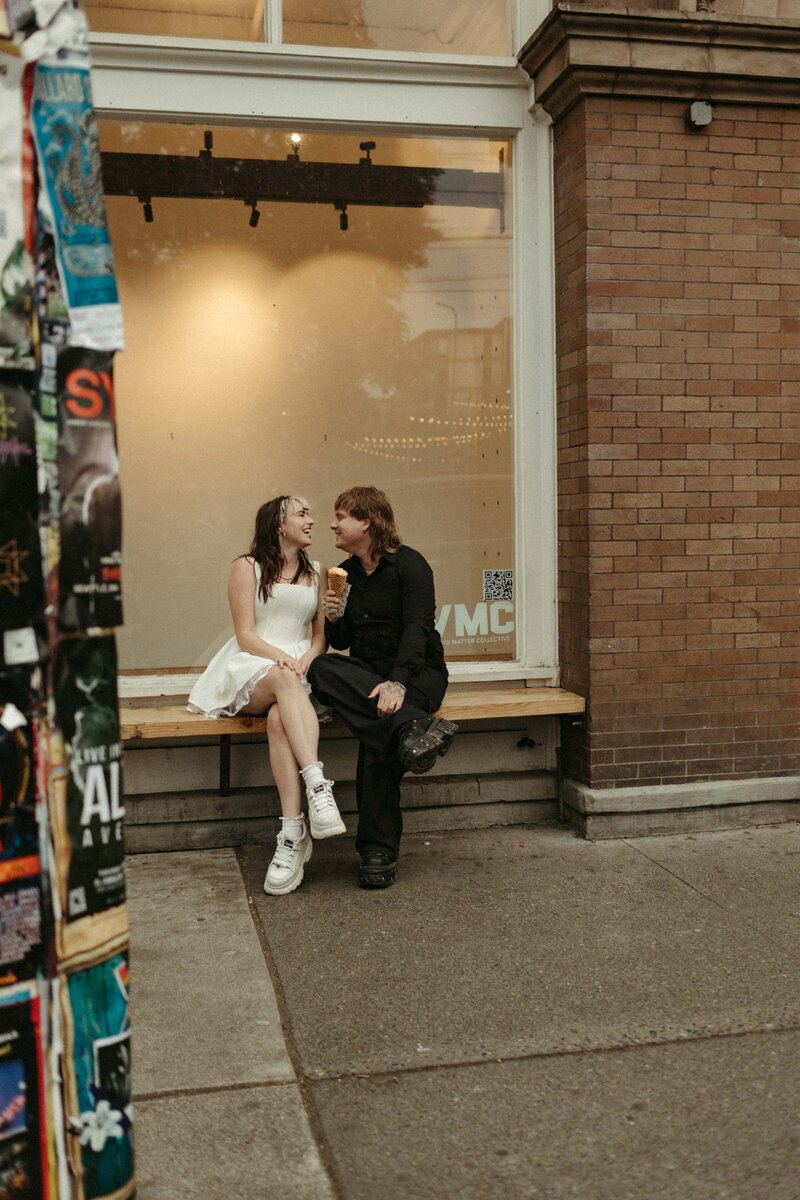 An edgy bride and groom share an intimate moment on a city bench following their carefree elopement